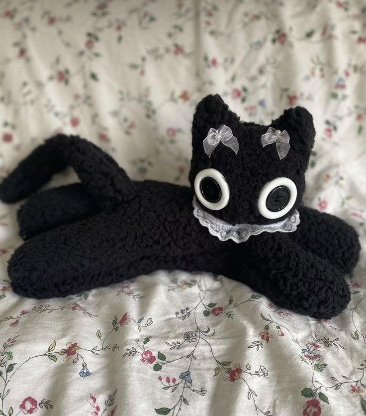 a black stuffed animal laying on top of a bed