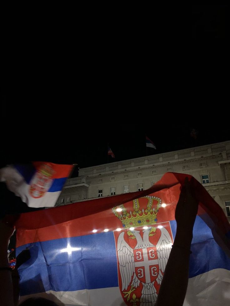 a large flag is being held in front of a building