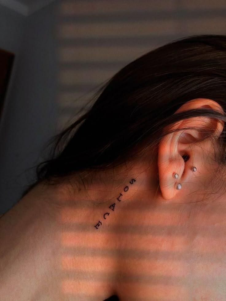 a woman with ear piercings on her back is looking down at the ground and has words written on it