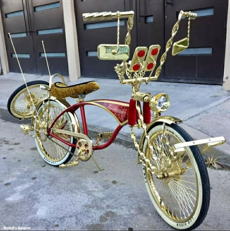 a red and gold bicycle parked in front of a garage