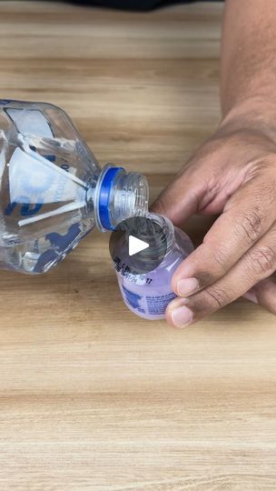 a person is opening up a water bottle on a wooden table with the lid open