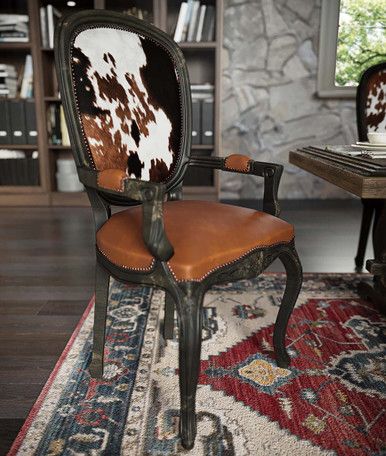 an old chair with cow hide on it in front of a bookcase and rug