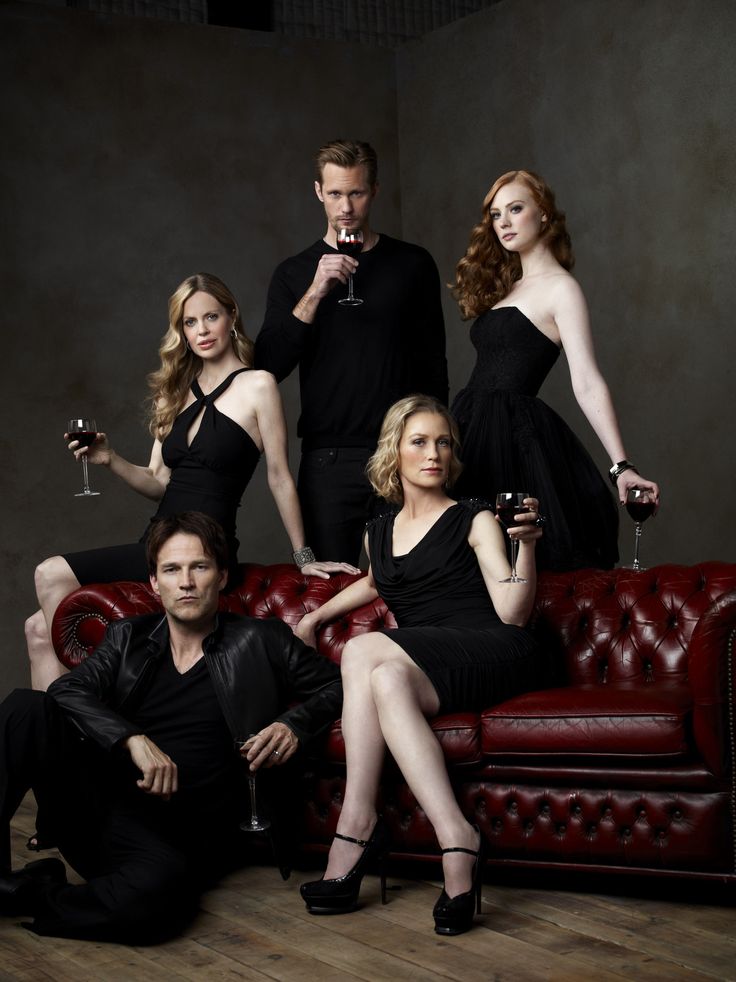 a group of people sitting on top of a red couch with wine glasses in their hands