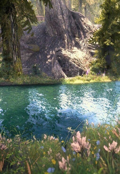 the water is crystal blue and green in this scene with rocks, trees, and flowers