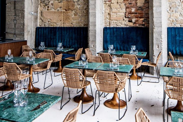 an empty restaurant with tables and chairs set up for lunch or dinner in front of a brick wall