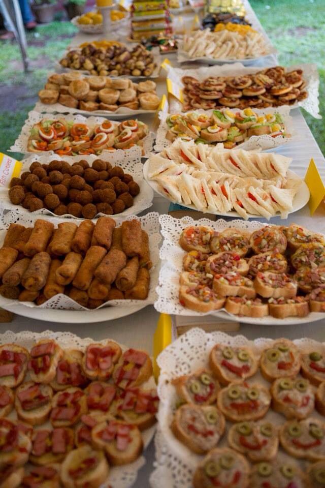 a table filled with lots of different types of food on white plates and yellow tables cloths