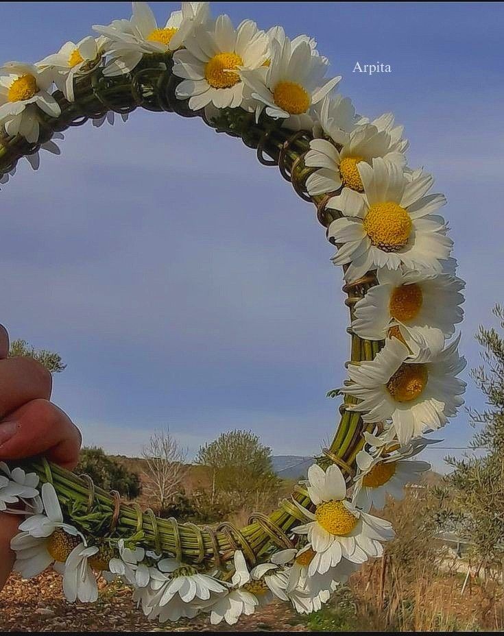 a hand holding a wreath made out of flowers