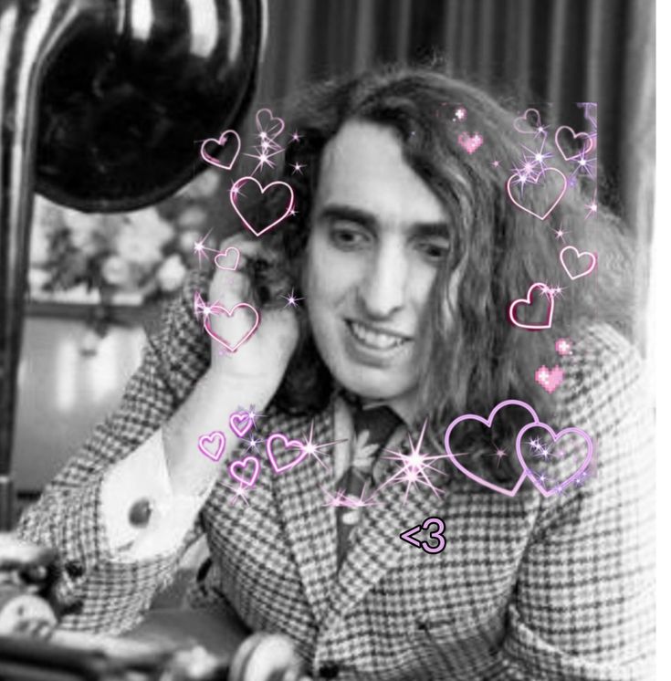 a black and white photo of a man with long hair sitting at a desk in front of a computer