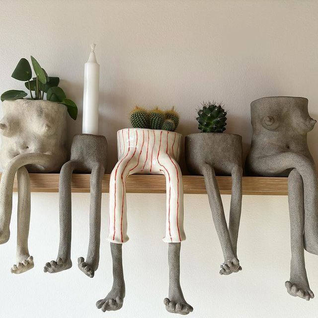 three cement figures sitting on top of a shelf next to succulents and candles