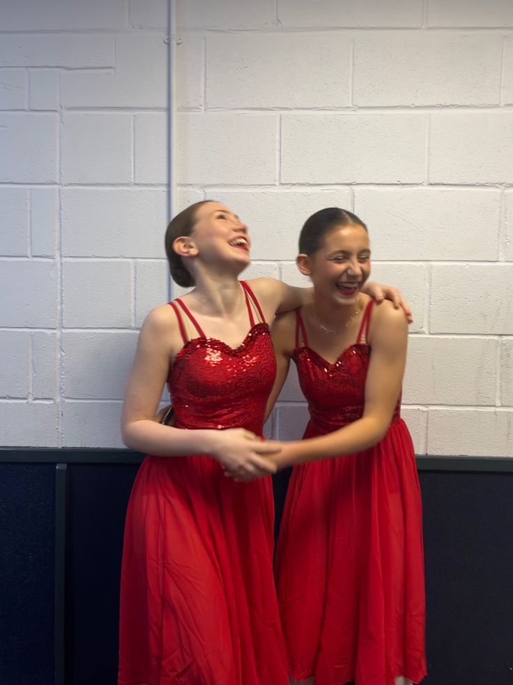 two girls in red dresses standing next to each other