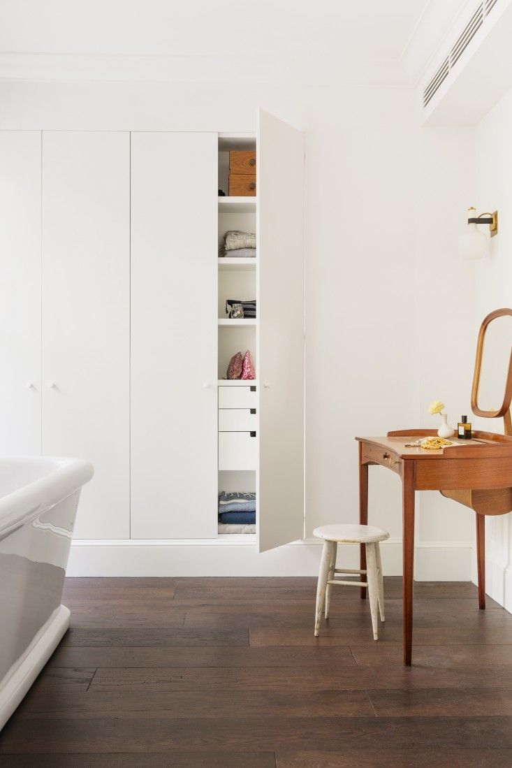 a white bathroom with a wooden desk and bathtub in the corner next to it