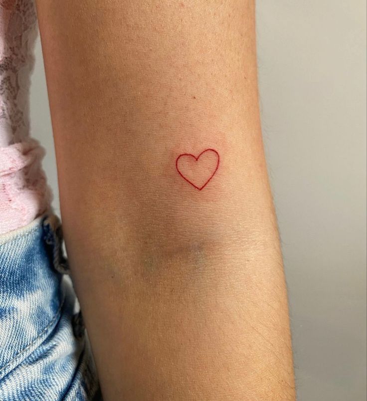 a small red heart tattoo on the arm