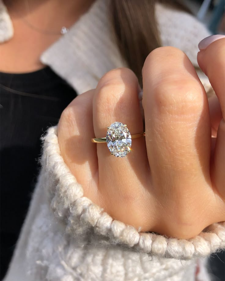 a woman's hand with a diamond ring on her finger, in front of the camera