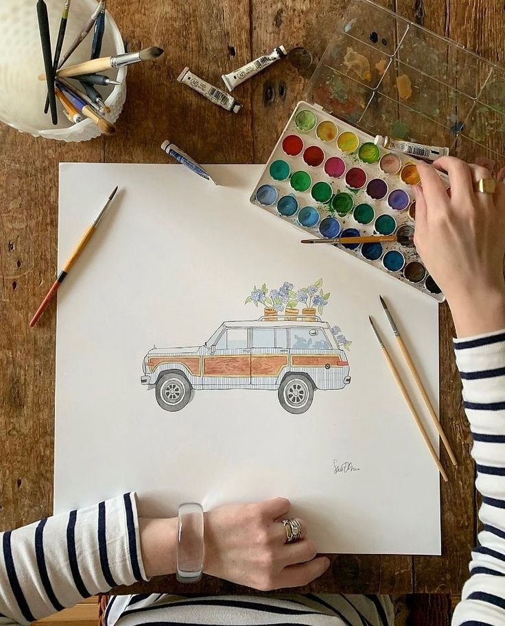 a woman is drawing on paper with watercolors