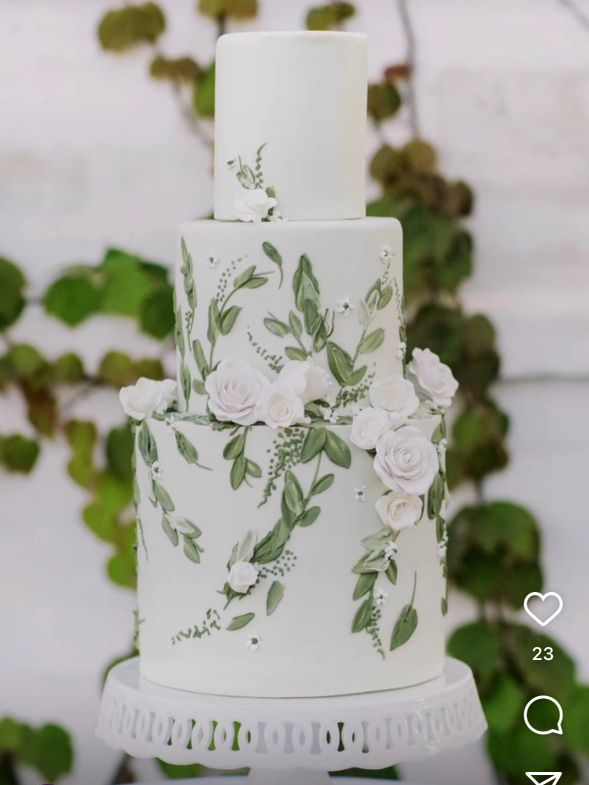 a white and green wedding cake with flowers on the top is sitting on a table