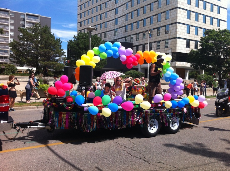 a parade float with balloons and people riding in the back