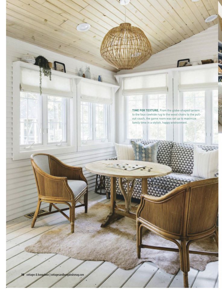 a living room with white walls and wooden floors, two wicker chairs and a round table