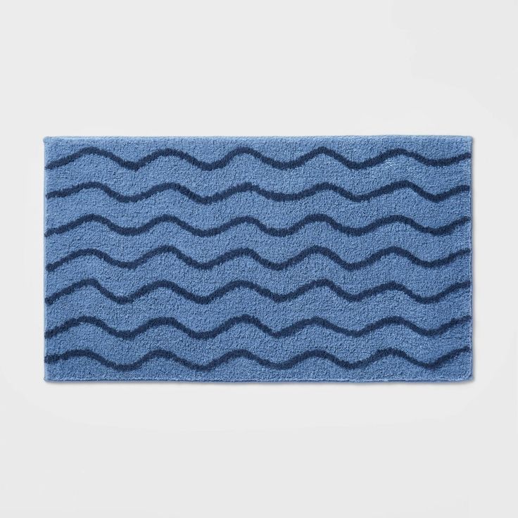 a blue bath mat with wavy waves on the front and back of it, against a white background