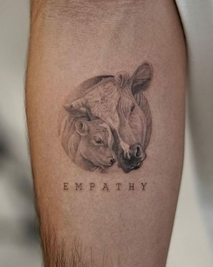 a tattoo on the leg of a man with two cows that say empathhy