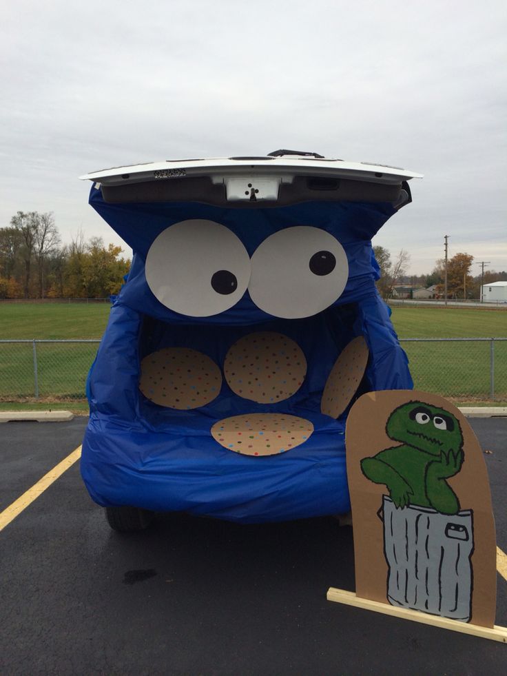 a blue car with an open hood and eyes sitting in a parking lot next to a cardboard cutout