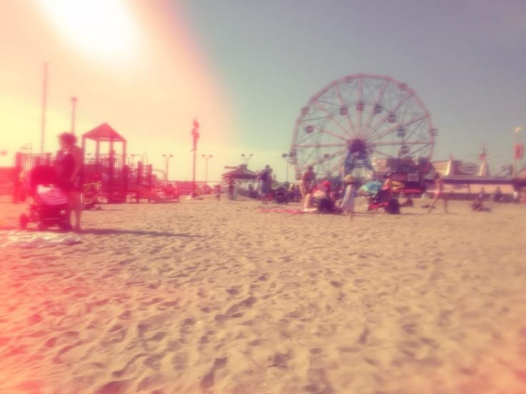 a ferris wheel sitting on top of a sandy beach next to a carnival rides area