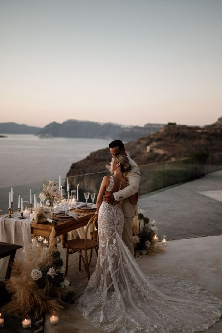 a bride and groom standing next to each other in front of a table with candles