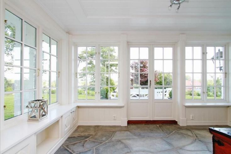 an empty room with large windows and stone flooring