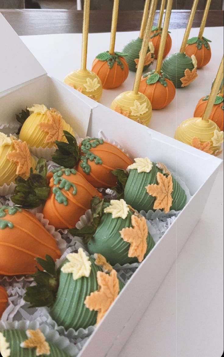 there are many cupcakes in the box with candles on them and pumpkins