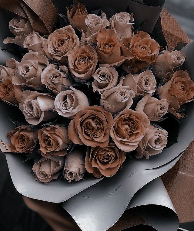 a bunch of brown roses sitting on top of a white and gray paper bouquets