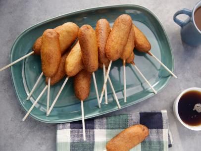 some fried food is sitting on a plate with toothpicks in it next to a cup of coffee