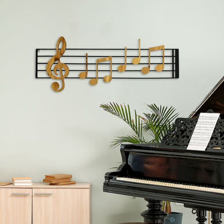 a piano with musical notes hanging on it's wall next to a potted plant