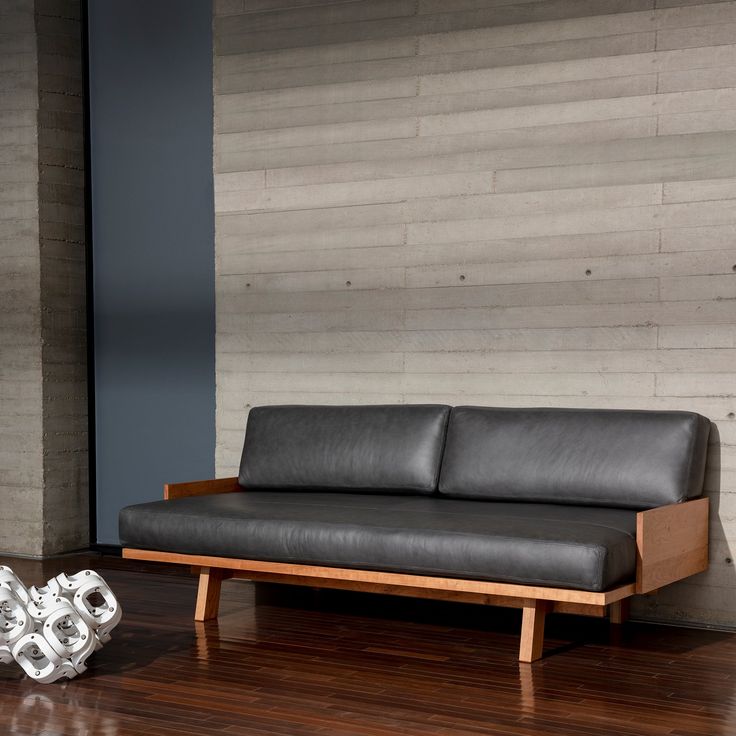 a black leather couch sitting on top of a hard wood floor next to a wall