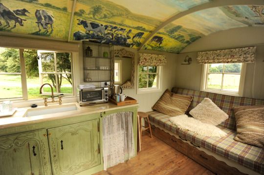 a kitchen and living room inside of a tiny house with painted ceiling murals on the walls