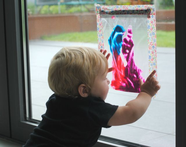 a little boy that is looking out the window at some art on display in front of him