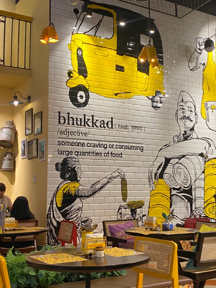 the interior of a restaurant with yellow chairs and brick wall murals on the walls behind them