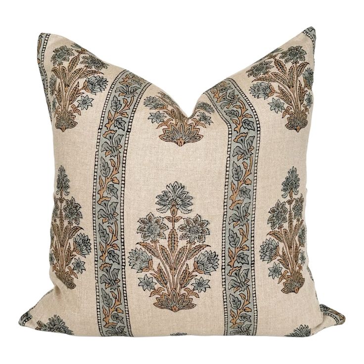 a beige pillow with blue and brown floral designs on the front, sitting on a white background