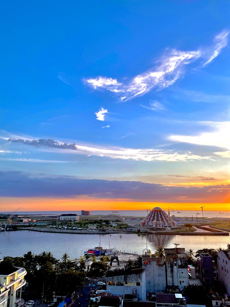 the sun is setting over some buildings and water