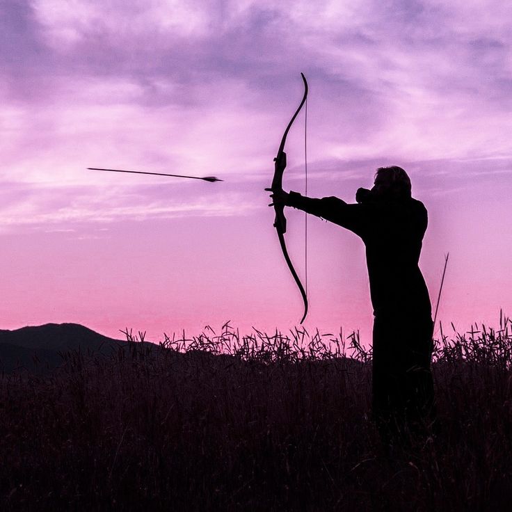 a man with a bow and arrow in the sunset