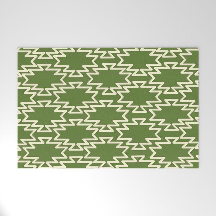 a green and white rug with an arrow pattern on the bottom, in front of a wall