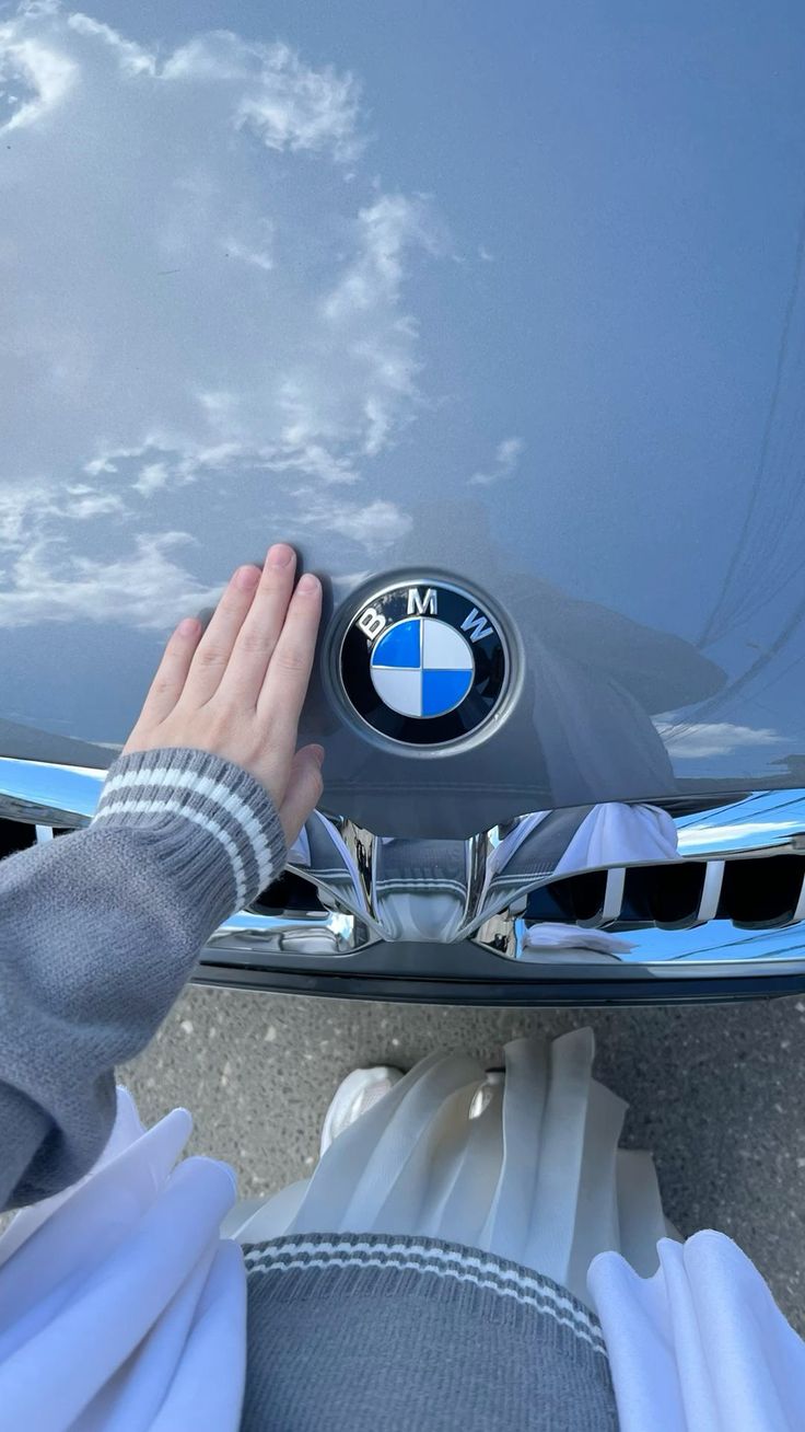 someone is holding their hand on the hood of a bmw car with its emblem in front of them