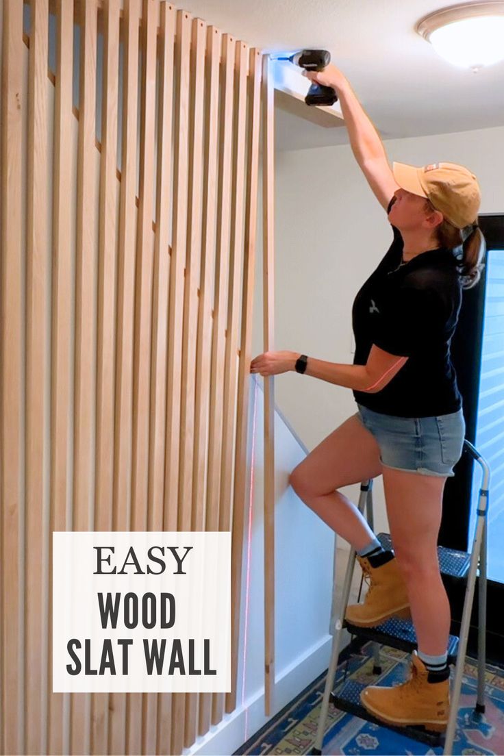 a woman standing on a stepladder using a wood slat wall