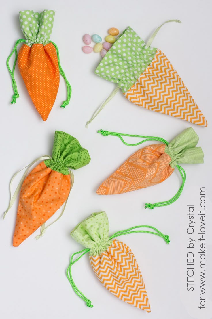 four carrots with green and orange bows on them are lined up in the shape of candy bags