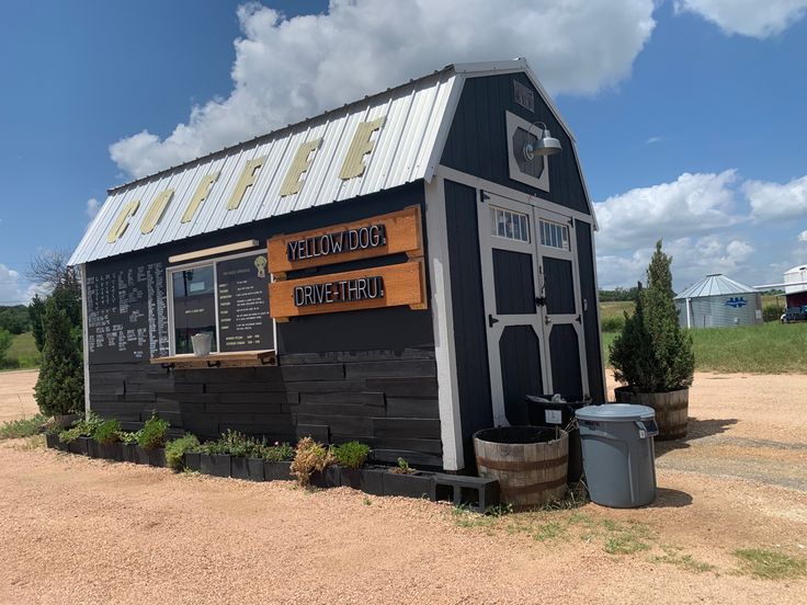 a small black building sitting on top of a dirt field