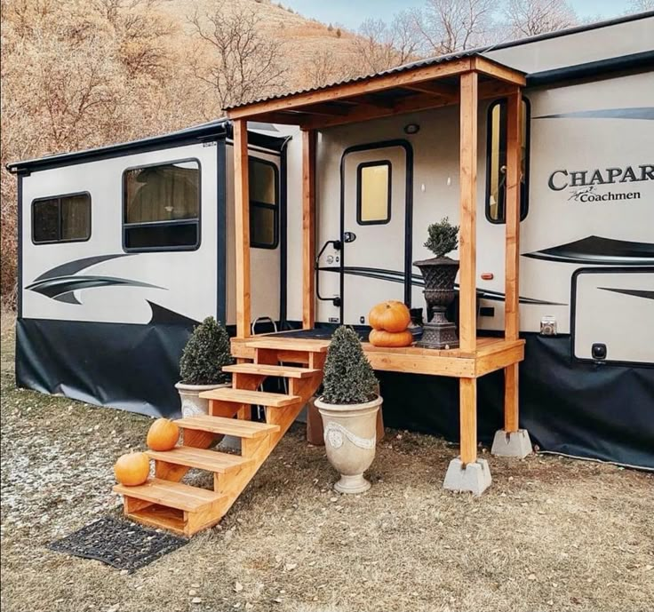 an rv with stairs leading up to it and pumpkins on the ground next to it