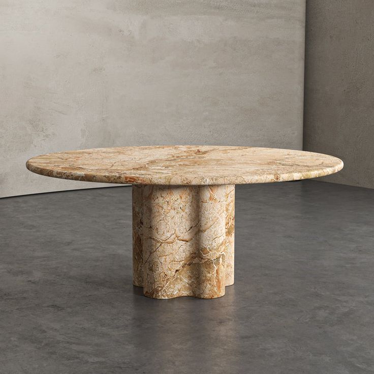 a round marble table sitting on top of a cement floor next to a white wall