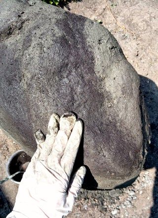 a gloved hand holding onto a large rock