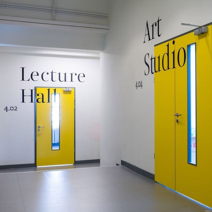 an art studio with yellow doors and black lettering on the wall, in front of white walls