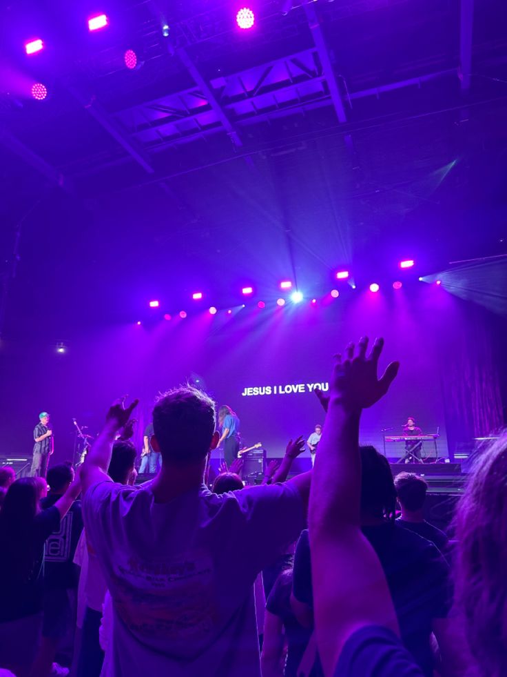 a group of people standing on top of a stage with their hands in the air