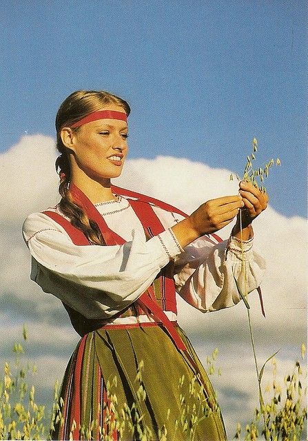 a woman is standing in the middle of a field holding flowers and looking at something