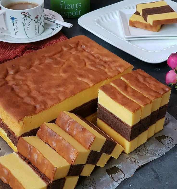 there is a cake that has been cut into squares and placed on the table with plates